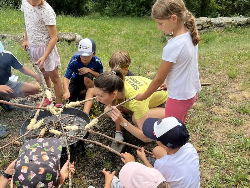 Kinder backen Stockbrot an der Feuerstelle im Wald