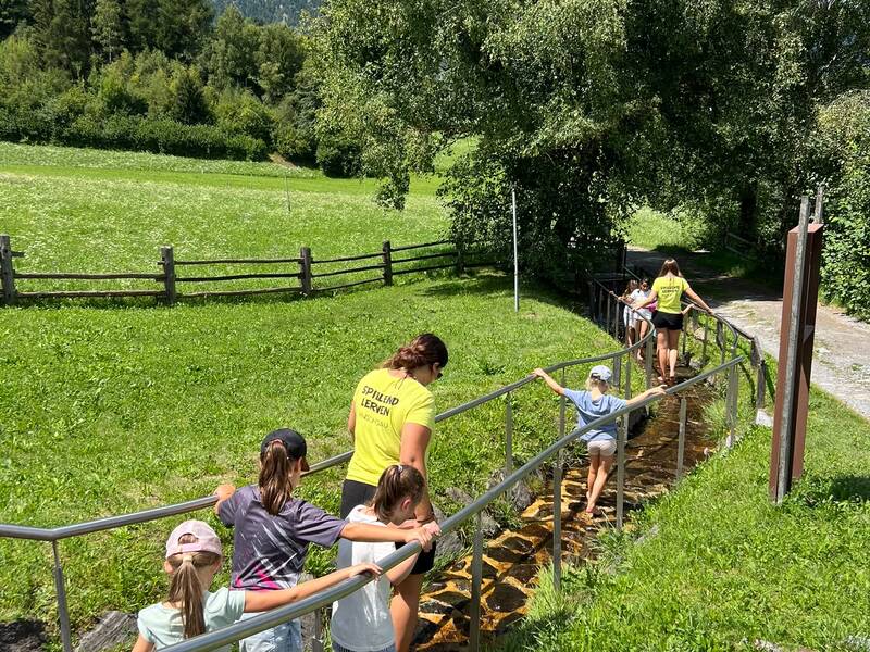 Kinder waten barfuß durch einen Waal